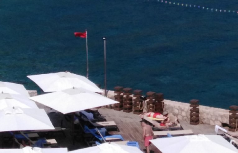 Crvena zastava na plaži u Dubrovniku, zabranjeno kupanje. Morem plutaju fekalije