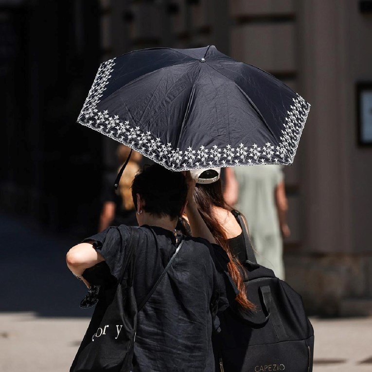 Zagrebačke ulice pune i po vrućinama, ljudi traže zaklon pod kišobranima