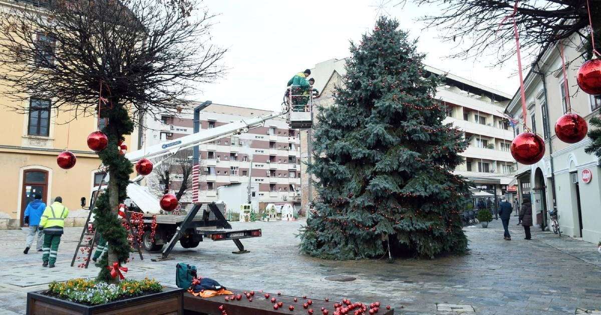 FOTO U centru Siska postavljen veliki bor, radnici ga ukrašavaju crvenim kuglicama