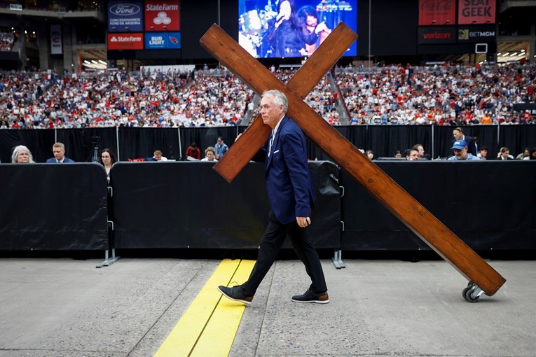 Ovo je fotografija s komemoracije Charlieju Kirku. Čovjek vuče križ s kotačićima