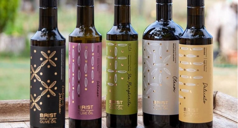 Assorted BRIST olive oil bottles with colorful labels displayed on a wooden surface.