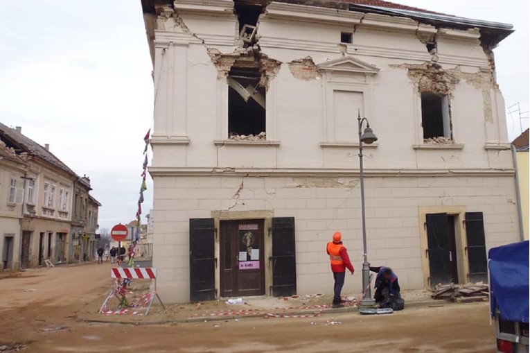 Centar: Radnici u Petrinji popravljaju stup, metar do sablasno rascvjetane zgrade