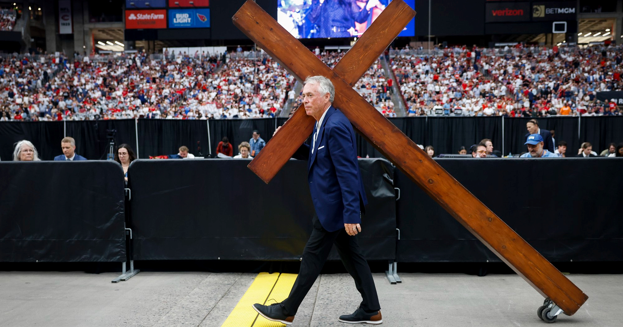 Ovo je fotografija s komemoracije Charlieju Kirku. Čovjek vuče križ s kotačićima