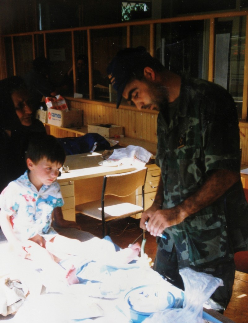 "Otišao sam u rat , kao dragovoljac, 26. 6. 1991. Na Baniji. Tada je počelo. U Glini. Na Baniji je i sve završilo. 17. 9. 1995. Akcija Una. 
Bio sam tada mladi liječnik. Iz HV sam izašao 31. 3. 1996.
Netko me ,na fotografiji,koju šaljem slikao i poslao mi je. Fotografija je nastala negdje pred ulazom u Dvor na Uni.
Dijete je bilo iz kolone izbjeglih Srba. Dva dana prije poginuli su mu majka i otac. U koloni. Napao ih je naš avion.
Našli su ga u nekom žbunju , trnju uz cestu i poveli sa sobom.
Sve mi je to rekla gospođa na fotografiji iza njega.Ona me zamolila da mu pomognem.
Bio je sav izgreban. Nije rekao niti jednu riječ. Nije pustio niti jednu suzu."