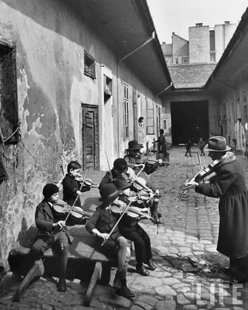 Romska djeca uče svirati violinu u dvorištu jedne kuće u jednom od siromašnijih kvartova Budimpešte, Mađarska, 1939.