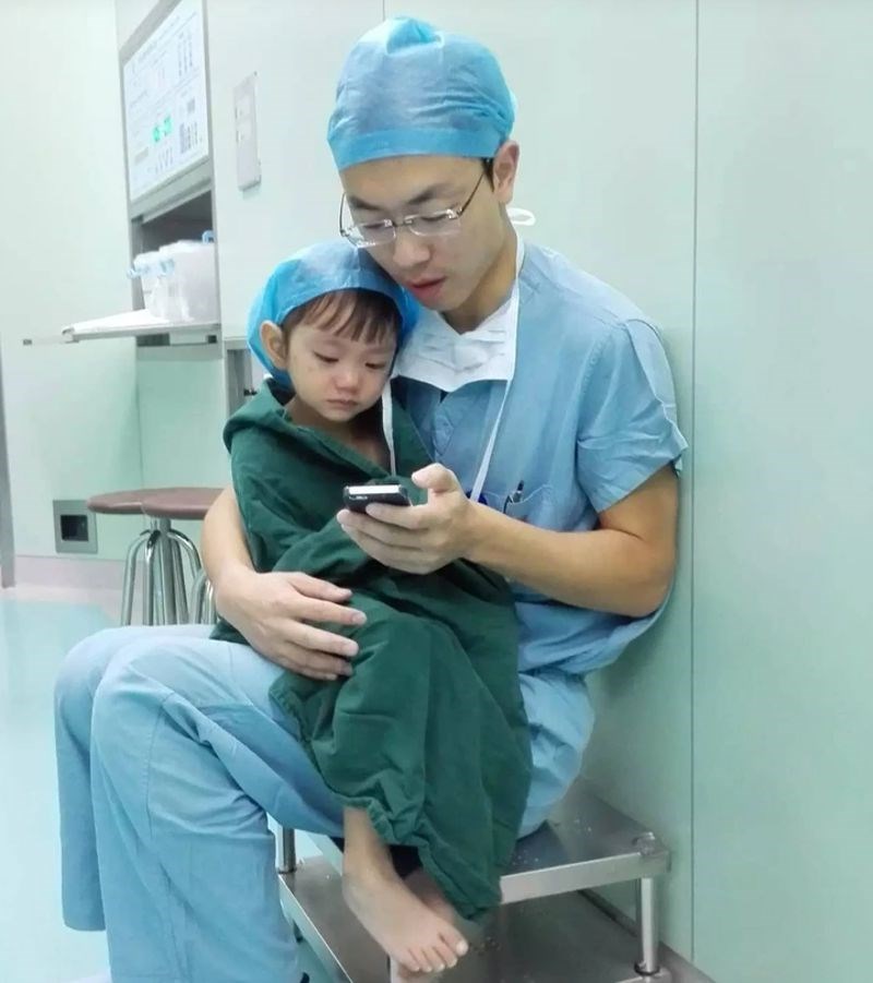 Kardiokirurg tješi uplakanu dvogodišnju djevojčicu puštajući joj crtiće prije operacije.