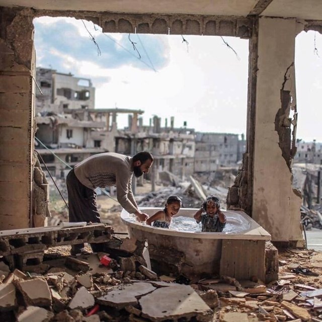 Otac kupa svoju kćer i nećakinju u njihovoj bombardiranoj kući u Gazi 2015. godine. Autor fotke: @emadsnassar
