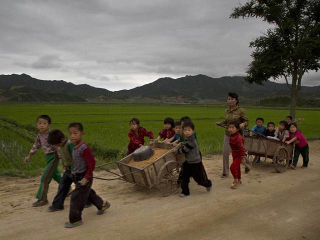 Mali školarci pomažu u popravljanju rupa na seoskoj cesti u sjevernokorejskoj pokrajini Sjeverni Hamgyong