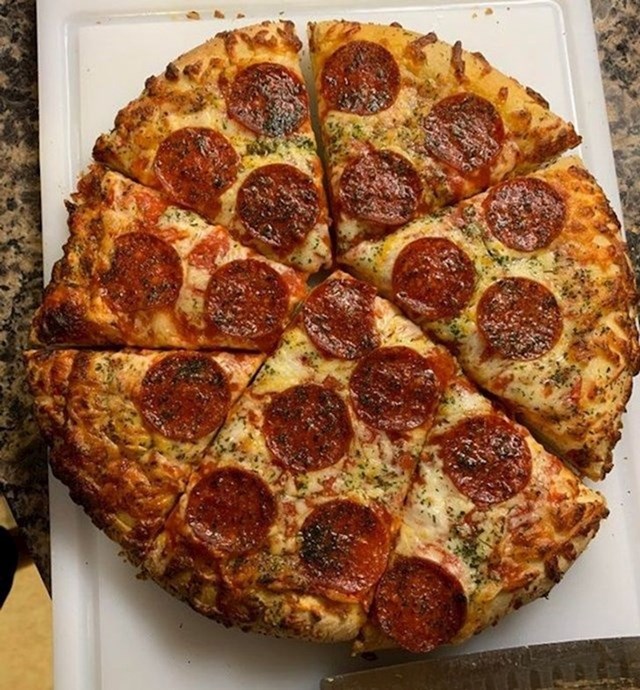 Tata reže kriške pizze tako što pazi da ne prereže kriške salame!