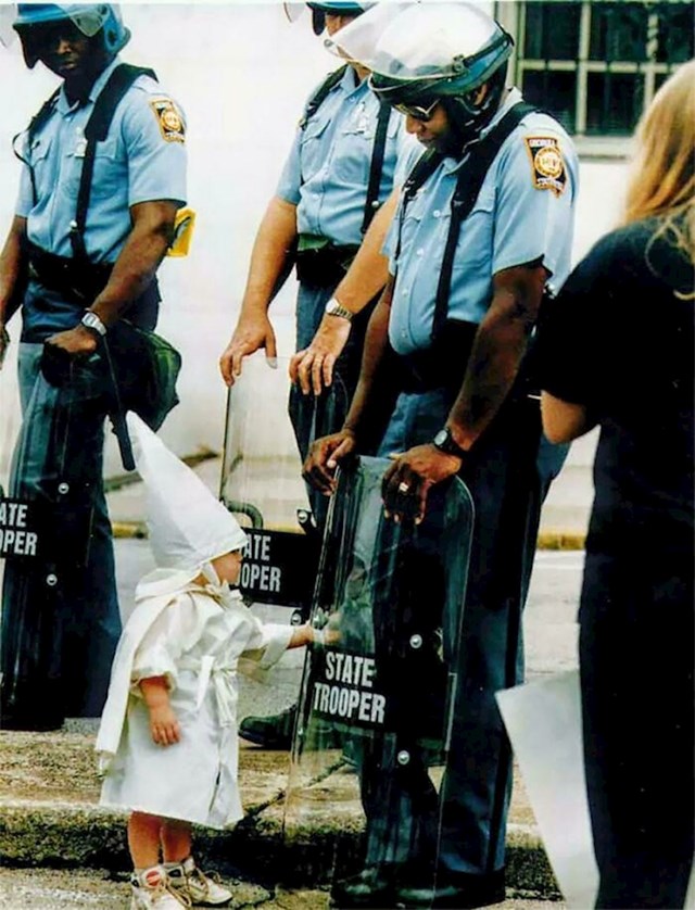 Prosvjed Ku Klux Klana 1992. u SAD-u. Cijeli besmisao ovoga prikazan je u fotografiji s prosvjeda na kojoj su dijete prosvjednik i policajac Afroamerikanac
