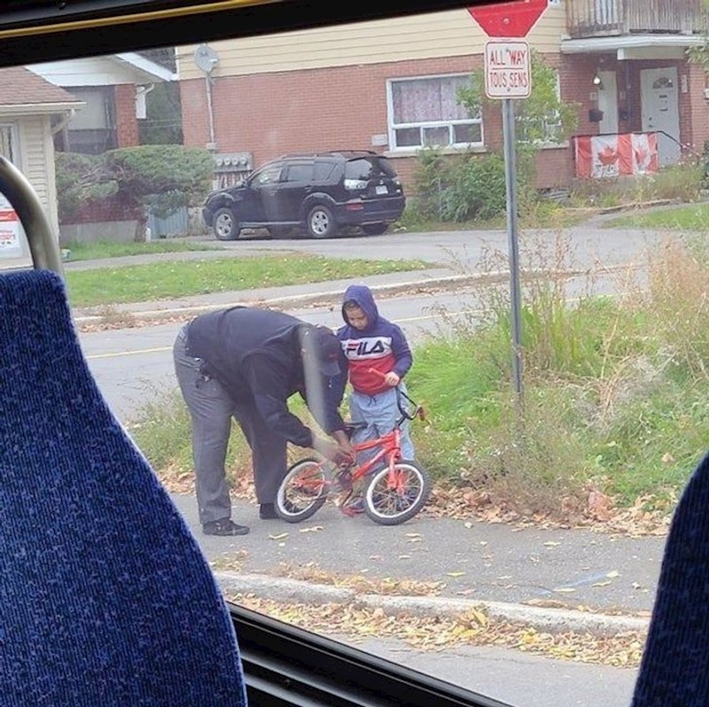 Čovjek pomaže klincu popraviti bicikl.