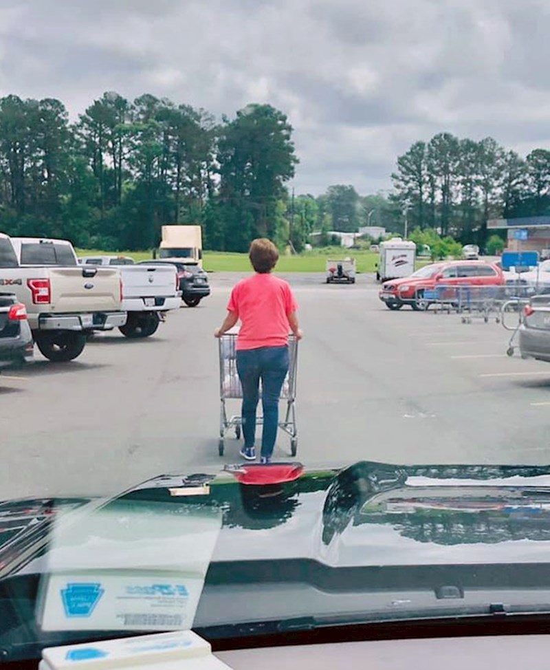 Ljudi koji hodaju s kolicima sredinom parkinga