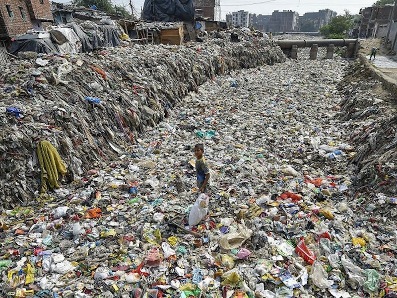 Dječak prikuplja predmete za reciklažu iz presušenog odvoda u Taimoor Nagaru u New Delhiju