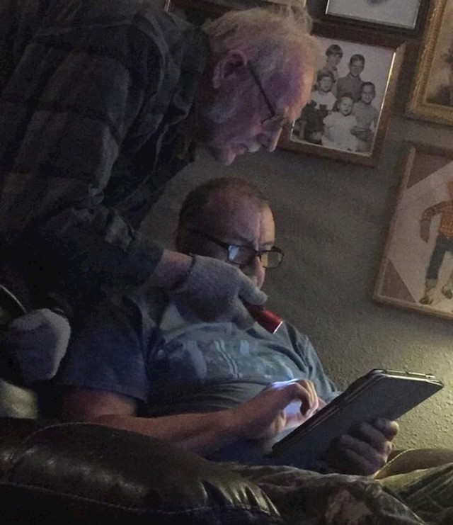 Djed svijetli baterisjkom lampom tatin tablet kako bi posvijetlili ekran da bolje vidi