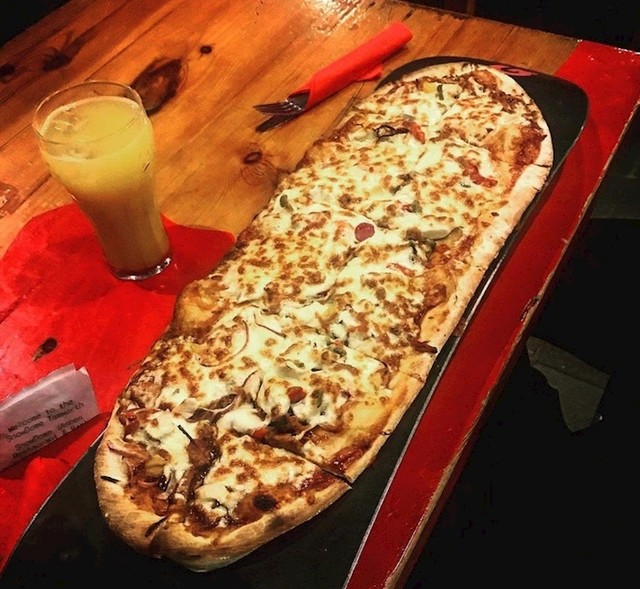 Kafić u parku za snowboard poslužuje pizzu na pravoj dasci za snowboard
